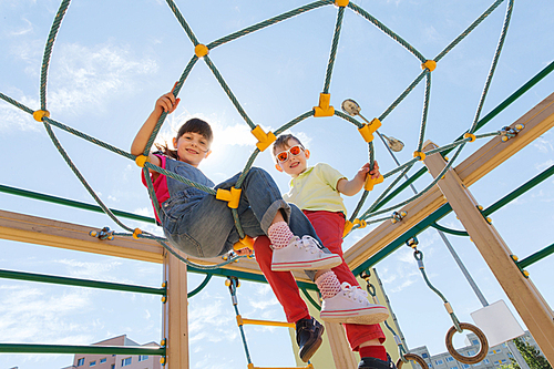 summer, childhood, leisure, friendship and people concept - group of happy kids on children playground climbing frame