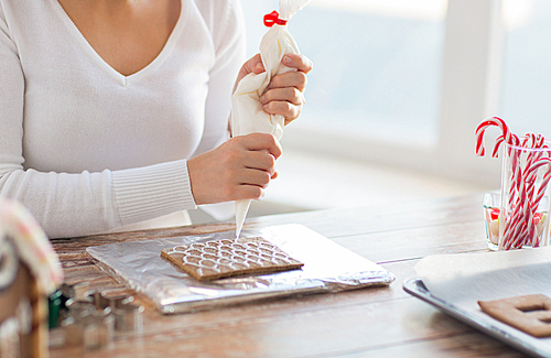 cooking, people, christmas and decoration concept - close up of happy woman making gingerbread houses at home