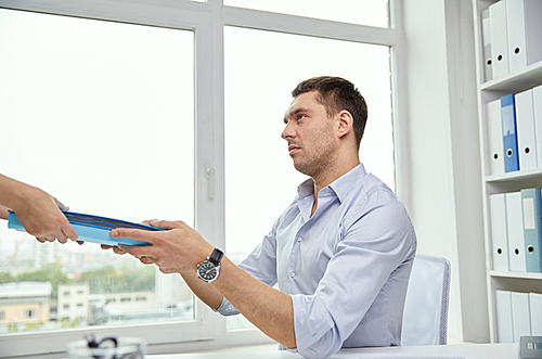 business, people and paperwork concept - businessman taking folder with papers from secretary in office