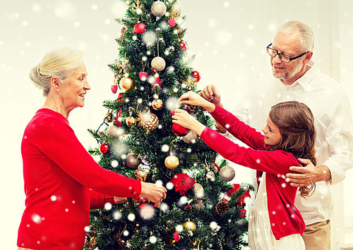 family, holidays, generation and people concept - smiling family decorating christmas tree at home