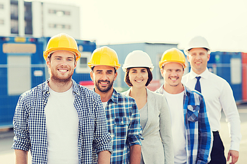 business, building, teamwork and people concept - group of smiling builders in hardhats outdoors