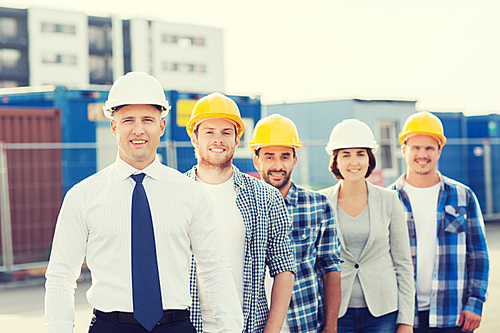 business, building, teamwork and people concept - group of smiling builders in hardhats outdoors