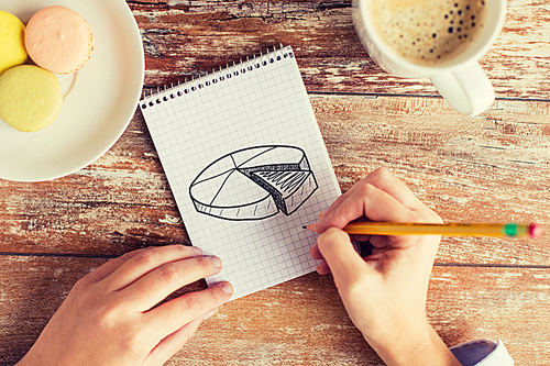 business, education and people concept - close up of female hands drawing chart in notebook with pencil, coffee and cookies on table