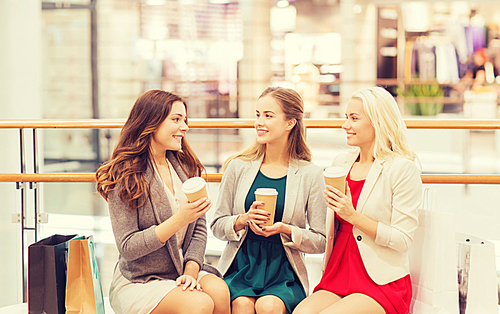 sale, consumerism and people concept - happy young women with shopping bags and coffee paper cups in mall