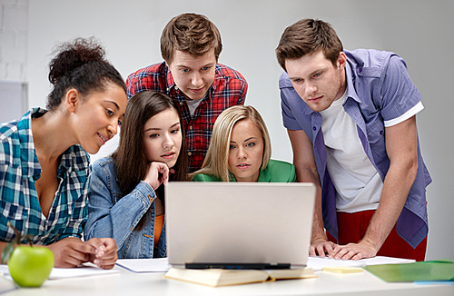 education, people, friendship, technology and learning concept - group of international high school students or classmates with laptop computer in classroom