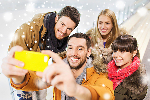 people, friendship, technology and leisure concept - happy friends taking selfie with smartphone on skating rink