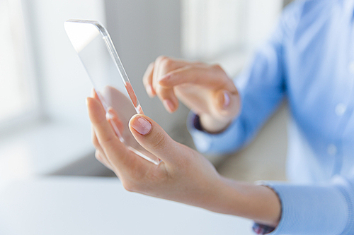 business, technology and people concept - close up of woman hand holding and showing transparent smartphone at office