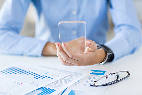 business, technology and people concept - close up of woman hand holding and showing transparent smartphone at office