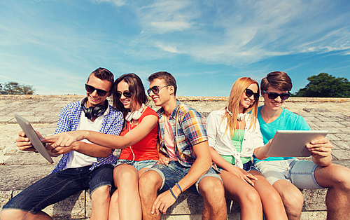 friendship, leisure, summer and people concept - group of smiling friends with tablet pc computers sitting outdoors