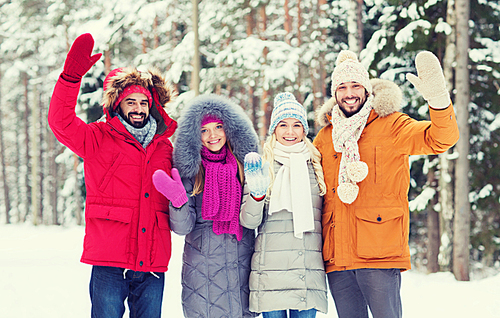 love, relationship, season, friendship and people concept - group of smiling men and women waving hands in winter forest