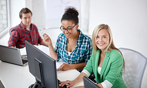 education, people, friendship, technology and learning concept - group of happy international high school students or classmates in computer class