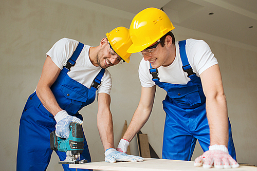 business, building, teamwork and people concept - group of smiling builders in hardhats with tools indoors