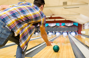 people, leisure, sport and entertainment concept - close up of young man throwing ball to alley in bowling club