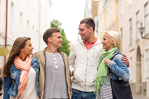 friendship, travel and vacation concept - group of smiling friends walking in the city