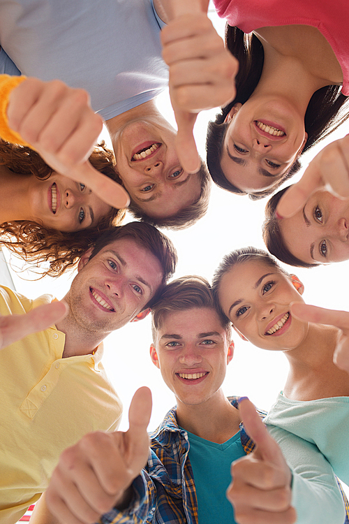 friendship, youth, gesture and people - group of smiling teenagers in a circle showing thumbs up