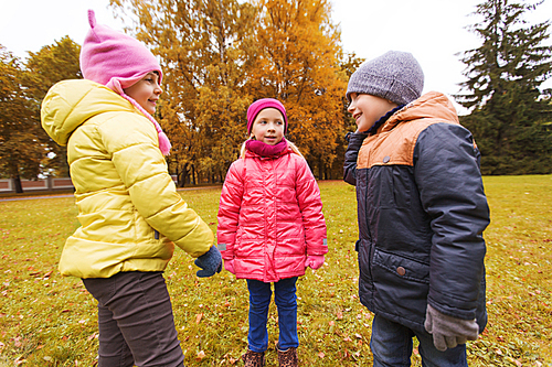 childhood, leisure, friendship and people concept - group of happy kids talking in autumn park