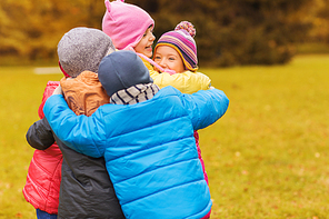 childhood, leisure, friendship and people concept - group of happy kids hugging in autumn park