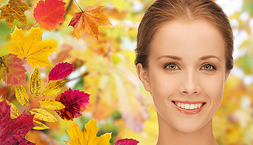 beauty, people and season concept - beautiful young woman face over autumn leaves background