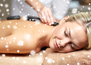 people, beauty, spa, healthy lifestyle and relaxation concept - close up of beautiful young woman having hot stone back massage in spa with snow effect