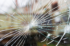 damage, violence, vandalism and danger concept - broken glass with cracks