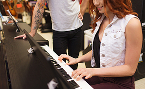 music, sale, people, musical instruments and entertainment concept - happy man and woman playing piano at music store