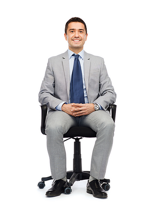 business, people and office concept - happy businessman in suit sitting in office chair