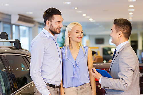 auto business, car sale, technology and people concept - happy couple with car dealer in auto show or salon