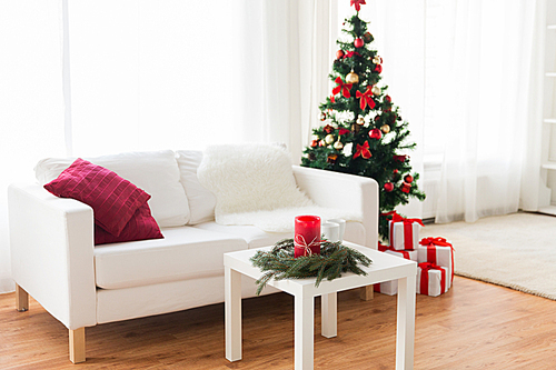 holidays, celebration, decoration and interior concept - sofa, table and christmas tree with gifts at home