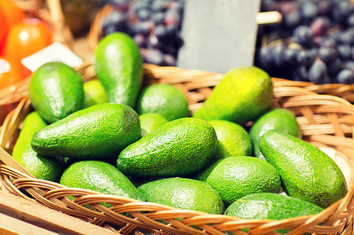 sale, shopping, vitamin c and  food concept - ripe avocado in basket at food market