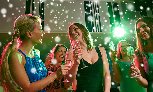 new year party, holidays, celebration, nightlife and people concept - happy young women with glasses of non-alcoholic champagne dancing in club and snow effect