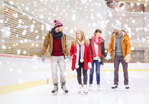 people, friendship, sport and leisure concept - happy friends on skating rink