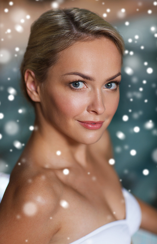 people, beauty, spa, healthy lifestyle and relaxation concept - close up of beautiful young woman in swimsuit at swimming pool with snow effect