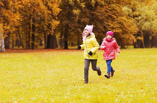 autumn, childhood, leisure and people concept - happy little girls playing tag game and running in park outdoors
