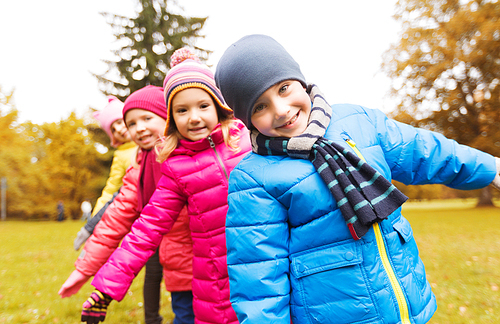 childhood, leisure, friendship and people concept - group of happy kids playing game and having fun in autumn park