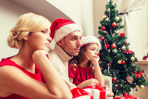 family, christmas, x-mas, winter and people concept - unhappy family at home with many gift boxes