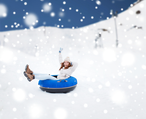 winter, leisure, sport, and people concept - happy teenage girl or woman sliding down on snow tube over mountain background