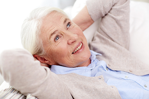 age, relax and people concept - happy smiling senior woman resting on sofa and dreaming at home