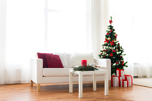 holidays, celebration, decoration and interior concept - sofa, table and christmas tree with gifts at home
