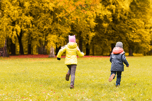 autumn, childhood, leisure and people concept - group of happy little kids playing tag game and running in park outdoors