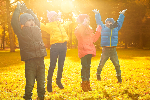 childhood, leisure, friendship and people concept - group of happy kids playing game and having fun in autumn park