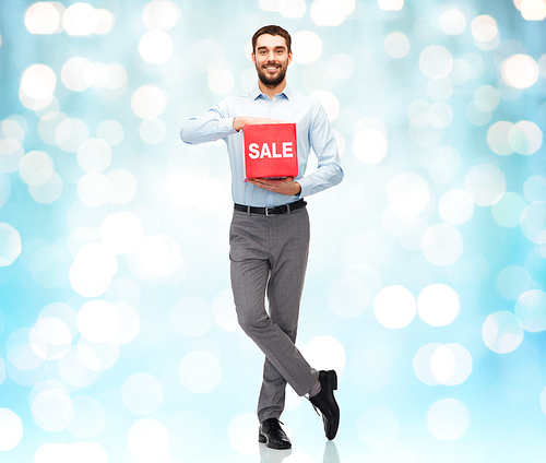 people, shopping, discount and holidays concept - smiling man holding red sale sign over blue lights background