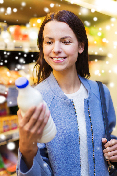 sale, shopping, consumerism and people concept - happy young woman holding milk bottle in market over snow effect