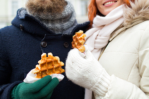 holidays, winter, christmas and people concept - close up of happy couple eating waffles outdoors