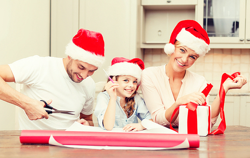 christmas, x-mas, winter,family, happiness and people concept - smiling family in santa helper hats with gift box