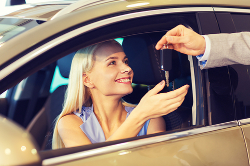 auto business, car sale, consumerism and people concept - happy woman taking car key from dealer in auto show or salon