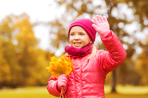 autumn, childhood, happiness and people concept - happy beautiful little girl with maple leaves bunch waving hand outdoors