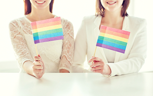 people, homosexuality, same-sex marriage, gay pride and love concept - close up of happy lesbian couple holding rainbow flags