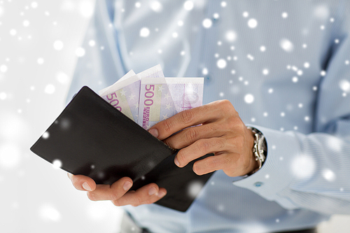 people, business, finances and money concept - close up of businessman hands holding open wallet with euro cash over snow effect