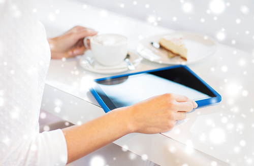 leisure, people, technology and lifestyle concept - close up of young woman hands with tablet pc computer drinking coffee and eating cake at cafe over snow effect