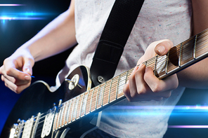 music, people, musical instruments and entertainment concept - close up female musician hands playing electric guitar with mediator